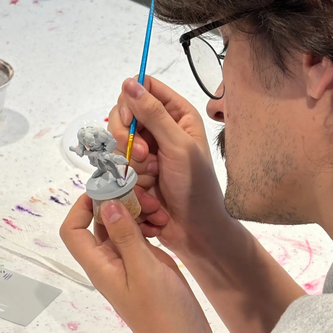 An artist's hand painting a miniature